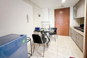 A compact kitchen with a dining table, chairs, and a refrigerator. - Strategic MTH Square Apt 1BR w/ Pool & Gym (East Jakarta)