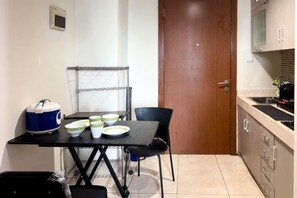 A small kitchen with a table, chairs, a kettle, and a microwave. - Strategic MTH Square Apt 1BR w/ Pool & Gym (East Jakarta)