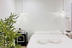 A hotel room with a bed, bedside table, and a potted plant.