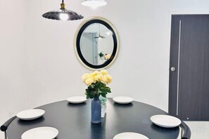 Een ronde tafel met witte borden, een vaas met gele bloemen en een spiegel aan de muur.