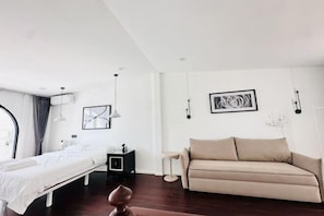 A modern, well-lit bedroom with a bed, a sofa, and a small bedside table.