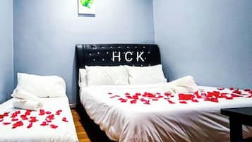 Een hotelkamer met twee bedden, waarvan één een hoofdeinde heeft met 'HCK' en de ander een egaal hoofdeinde. Beide bedden zijn voorzien van witte lakens en kussens.