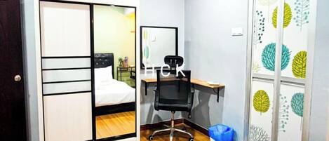 A room with a bed, a desk, a chair, and a wardrobe with a mirror.