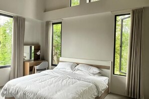 Ein Schlafzimmer mit einem Bett, einem Schreibtisch und einem Stuhl. Es gibt Fenster mit Vorhängen.