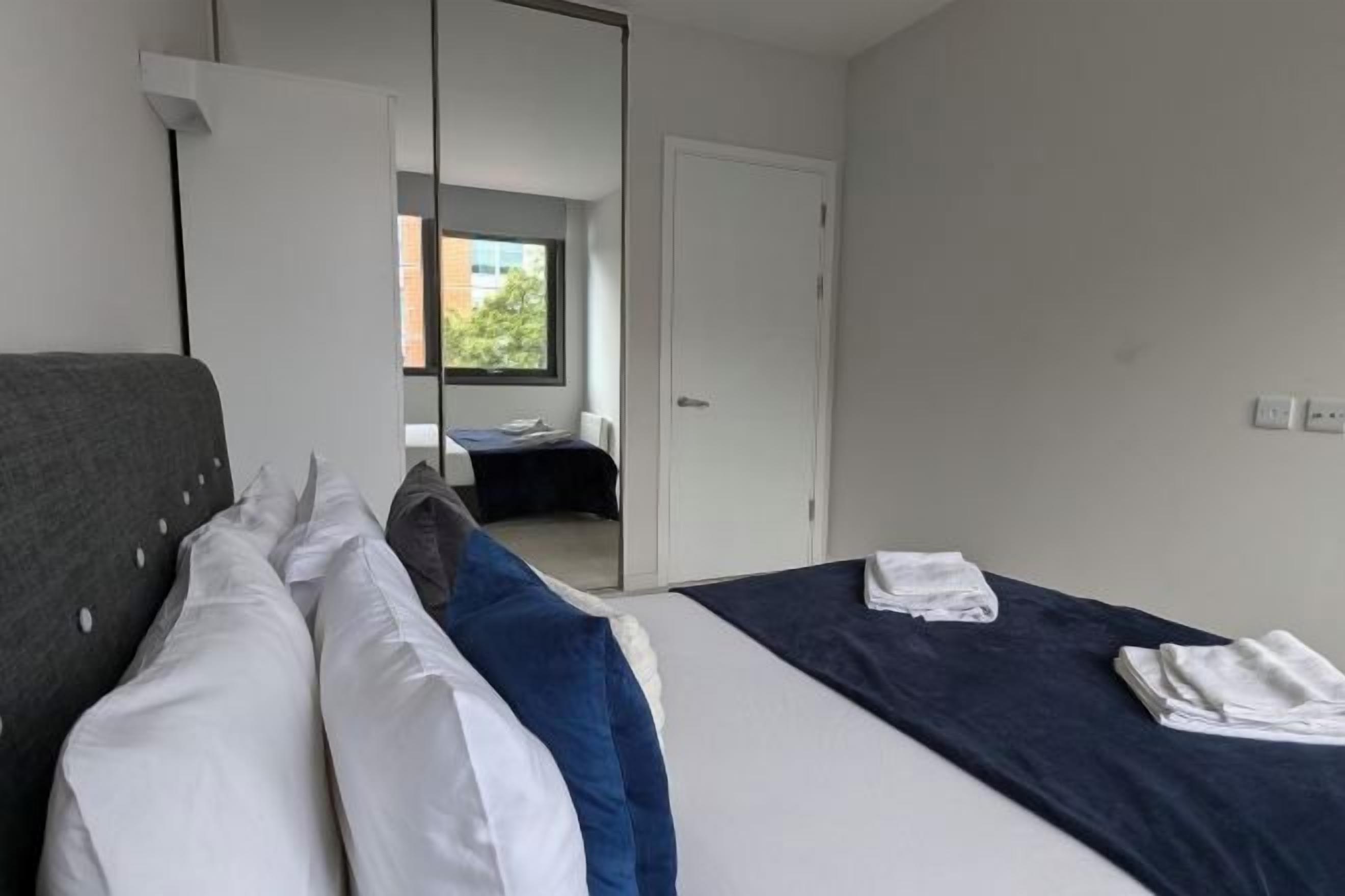A modern hotel room with a bed, a wardrobe, and a view of the outside.