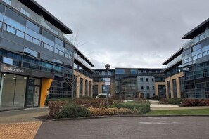 A modern building with large glass windows and a central courtyard. - Modern 1 Bed Apt Near Ascot- with parking (Bracknell)