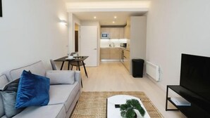 Een modern appartement met een woonkamer, eetgedeelte en kitchenette.