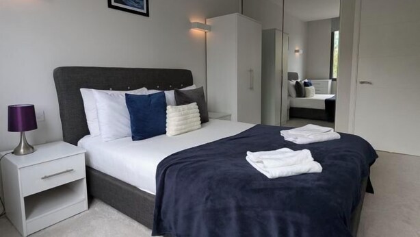 Een moderne slaapkamer met een bed, nachtkastje en een kledingkast.