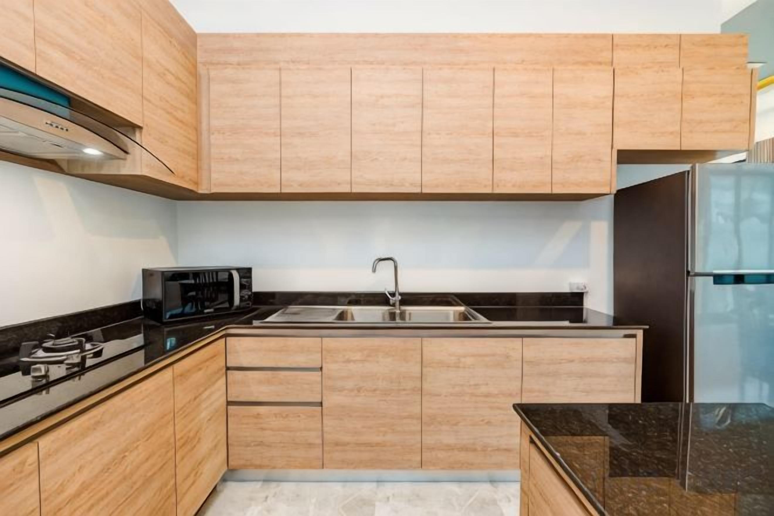 A modern kitchen with wooden cabinets, a stainless steel sink, and a black countertop.