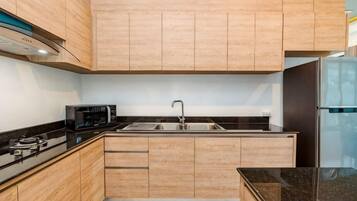 A modern kitchen with wooden cabinets, a stainless steel sink, and a black countertop.