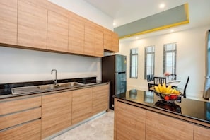 A modern kitchen with wooden cabinets, a stainless steel sink, and a black refrigerator.