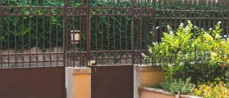 A gated entrance with a metal gate and a concrete pathway leading to a building.