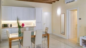A dining area with a wooden table and chairs, a white cabinet, and a door leading to another room. - Juliet House (Verona)
