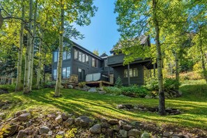 A modern two-story house with a large deck and a stone foundation. - Evergreen Escape – Home for 10 (Vail)