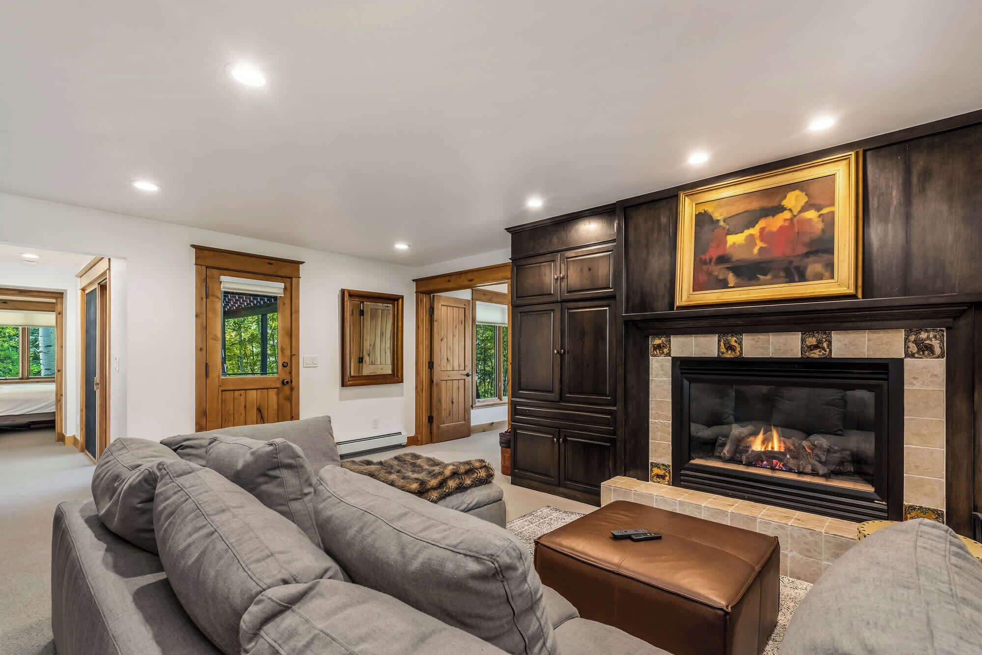 A living room with a fireplace, grey sofas, and wooden cabinets.