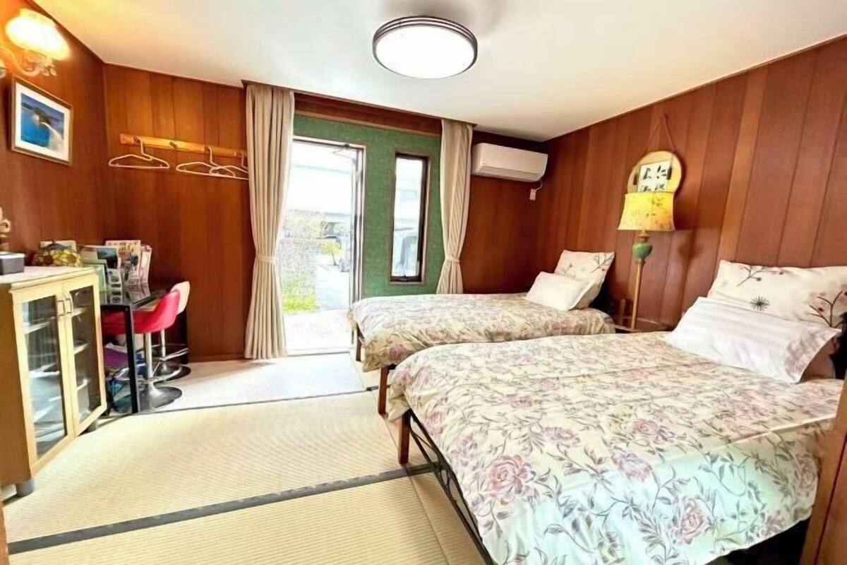 A room with two beds, a desk, a chair, and a window.