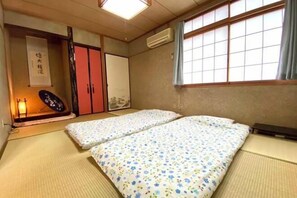 A traditional Japanese room with tatami flooring, a futon bed, sliding doors, and a shoji screen. - HAMANOCHOSYOUIN GuestHouse (Takamatsu)
