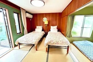 Una habitación con dos camas, una ventana y una lámpara.