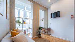 Un salon moderne avec un canapé, un téléviseur à écran plat, un coin repas et une grande fenêtre.