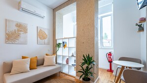 Un salon moderne avec un canapé, une table basse, une plante en pot et une bibliothèque.
