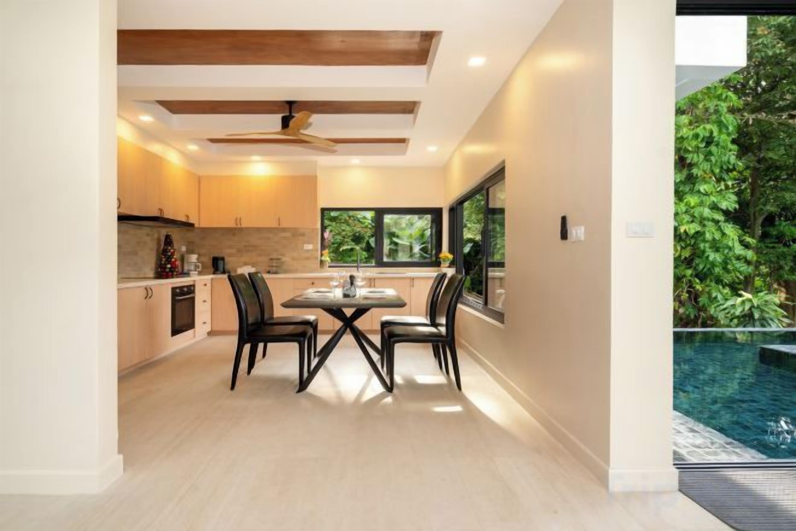 A modern kitchen with a dining area, a ceiling fan, and a view of a swimming pool.