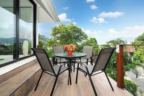 An outdoor patio with a round table and chairs, a vase with flowers, and a view of greenery and mountains. - patong hill 3 villa (Phuket)