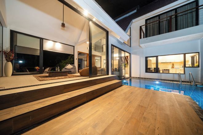 Una casa moderna con piscina, ventanas amplias y una escalera que lleva al piso superior.