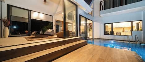 Una casa moderna con piscina, ventanas amplias y una escalera que lleva al piso superior.