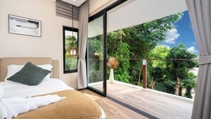Un dormitorio con un amplio ventanal corredero que da a un balcón con vistas a árboles y al cielo.