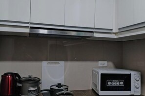 Una cocina con microondas, tetera y olla.