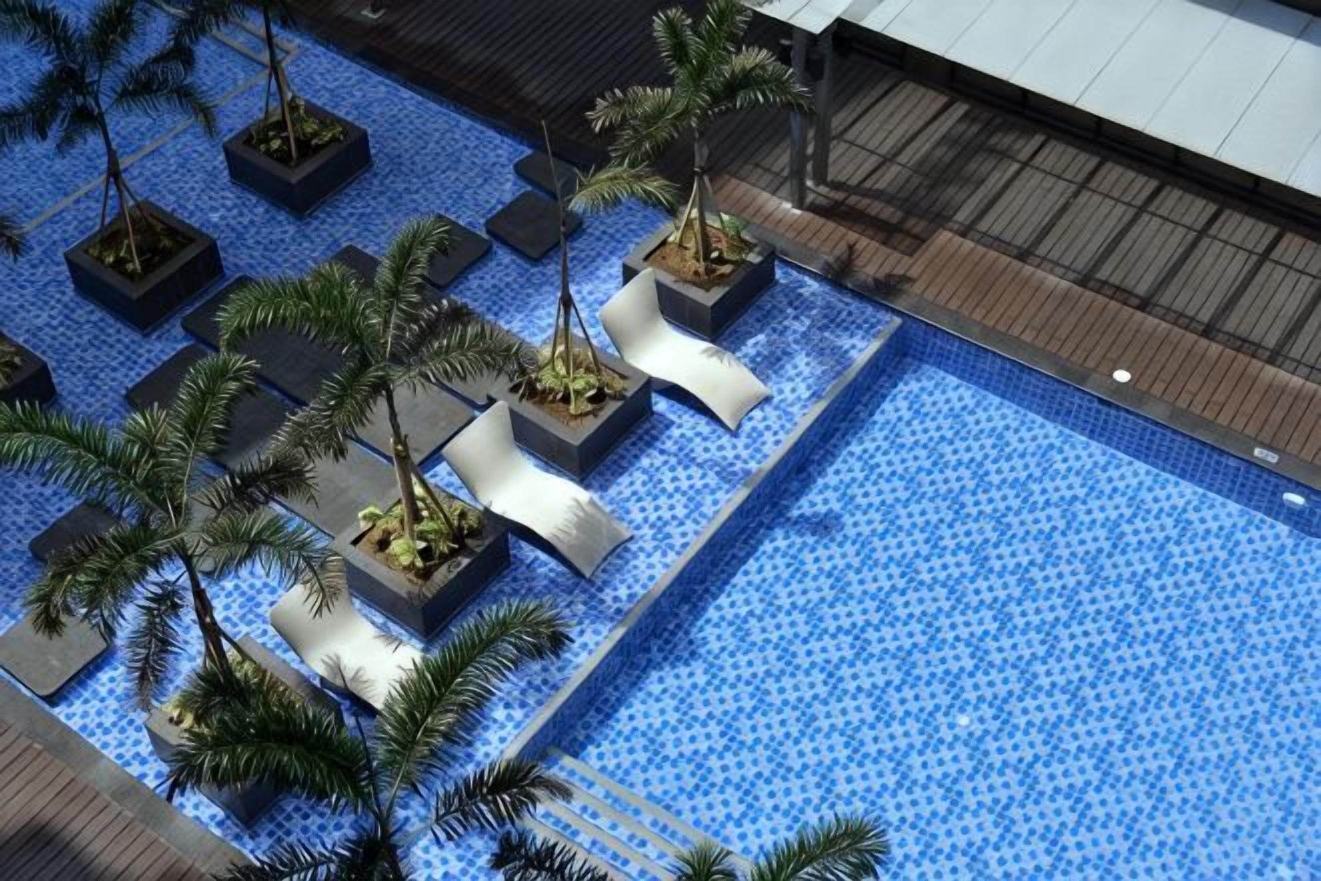 A rooftop pool with geometric planters and palm trees.