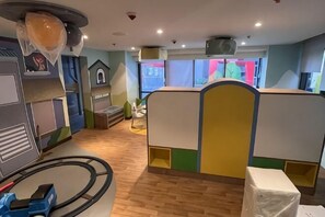 Ein Kinderspielbereich mit Rundlauf, Spielgeräten und einem Fenster mit Blick.