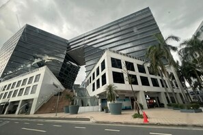 Een modern gebouw met een uniek, hoekig ontwerp, grote ramen en een verhard gebied met potplanten.