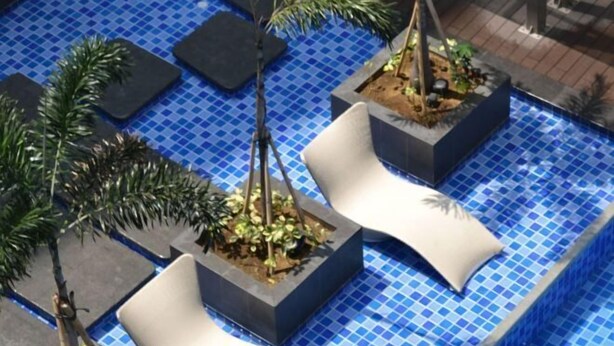 A pool area with tiled flooring, planters with plants, and white lounge chairs. - Near MOA beside Okada Pet Friendly 1BR 3 pax WIFI 8T (Paranaque)