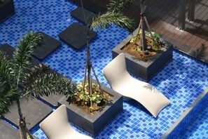 A pool area with tiled flooring, planters with plants, and white lounge chairs. - Near MOA beside Okada Pet Friendly 1BR 3 pax WIFI 8T (Paranaque)