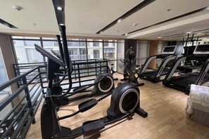 Een sportschool met loopbanden, elliptische trainers en een roeimachine.