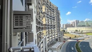 A multi-story residential building with balconies, a curved road, and a large building in the background. - Near MOA beside Okada Pet Friendly 1BR 3 pax WIFI 8T (Paranaque)