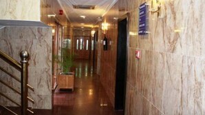 A marble-floored hallway with a staircase on the left, a reception desk on the right, and a sign indicating the location of the elevators. - Sunfit International Limited (Lagos)