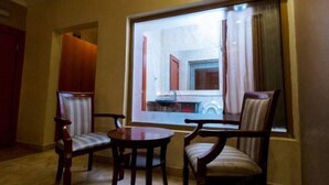 A room with a large window, two wooden chairs, a small table, and a red cabinet. - Sunfit International Limited (Lagos)
