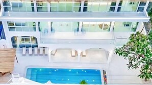 A multi-level hotel with a large pool, outdoor seating areas, and a view of the surrounding landscape. - Metero Garden Swimming Pool Villa (Pattaya)