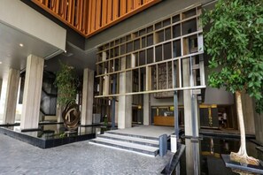 Un edificio moderno con una recepción, una escalera que sube a un nivel superior y una planta de interior grande.