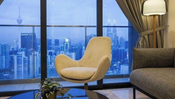 A modern room with a large window, a cushioned chair, a sofa, and a lamp. - Lucentia Residence at Kuala Lumpur by Dreamcloud Sdn Bhd (Kuala Lumpur)