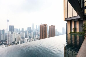 Un bâtiment moderne doté d’une piscine à débordement sur le toit, offrant une vue panoramique sur les toits de la ville.