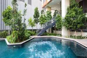Una piscina interior rodeada de abundante vegetación y una escalera.