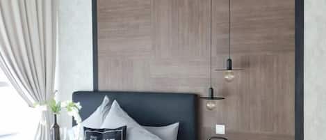 Un dormitorio moderno con una cama, una mesita de noche con un jarrón y un libro, una lámpara de pared y un panel decorativo.