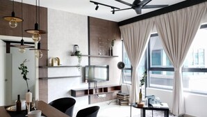 Un salon moderne avec un téléviseur à écran plat, des chaises noires, une table à manger et un ventilateur de plafond.