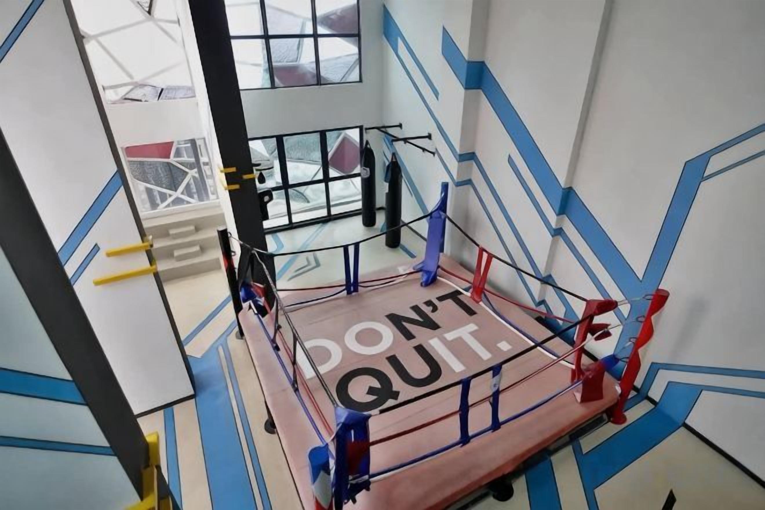 Un ring de boxeo con mensajes motivacionales y una ventana al fondo.