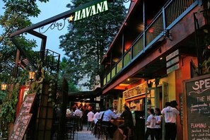 Un restaurant appelé «HAVANA» propose des places assises en plein air et affiche sur un panneau les plats à la carte, notamment «FLAMING» et «THE H».