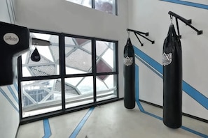 Een sportschool met bokszakken, een raam met uitzicht en een blauw-wit wandontwerp.