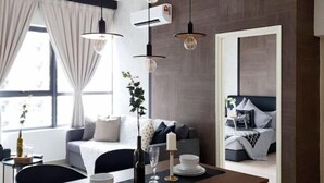Une chambre d’hôtel moderne dotée d’une grande fenêtre, d’un canapé, d’une table à manger avec une bougie et d’un ventilateur de plafond.